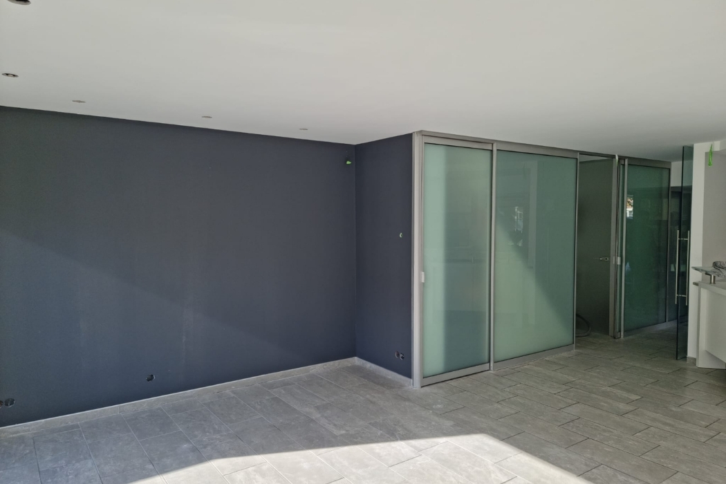 Woonruimte met donkere accentwand, licht plafond en een brede glazen opening